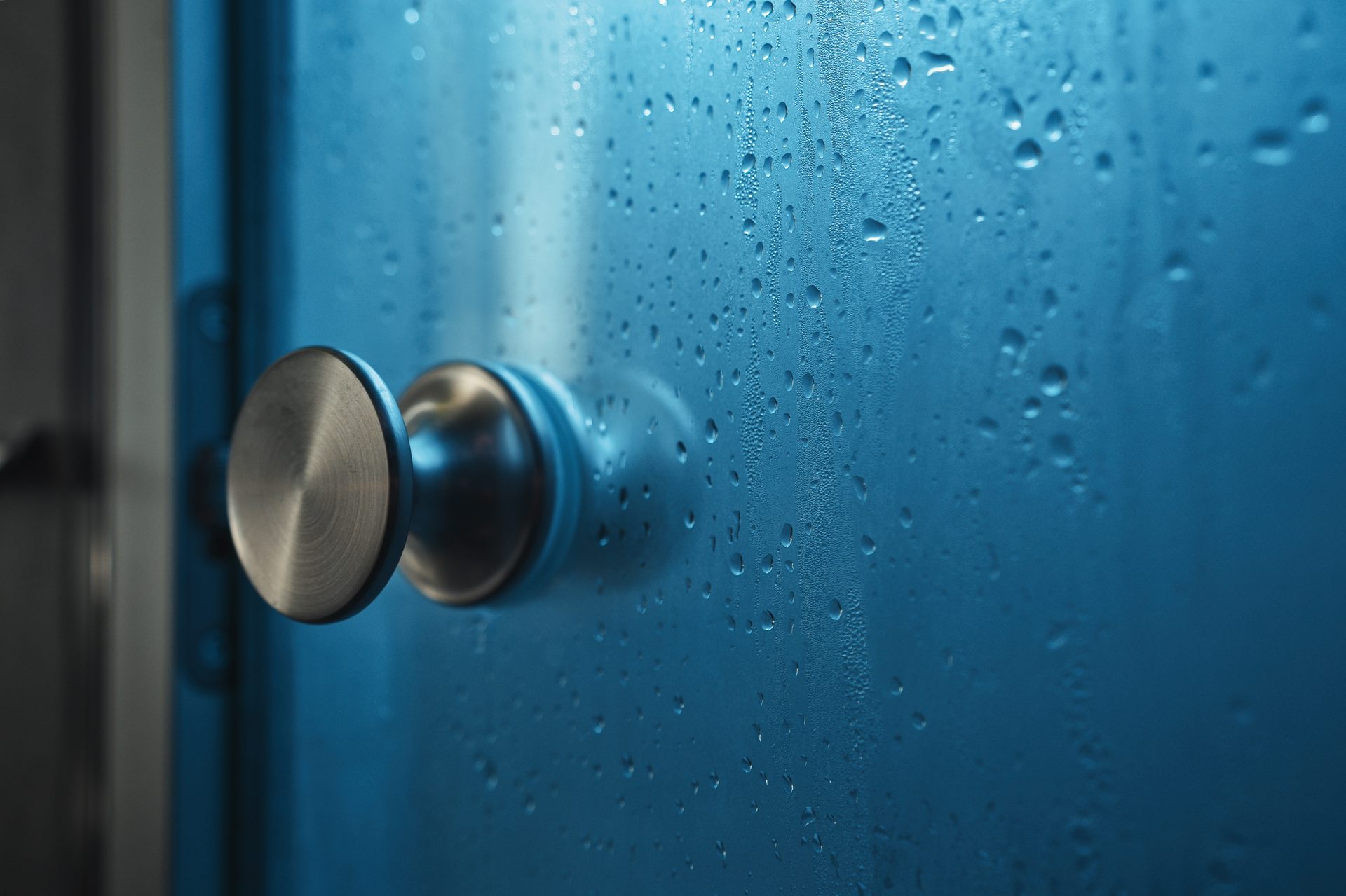 Vitre de douche couverte de gouttes dans la lumière bleue