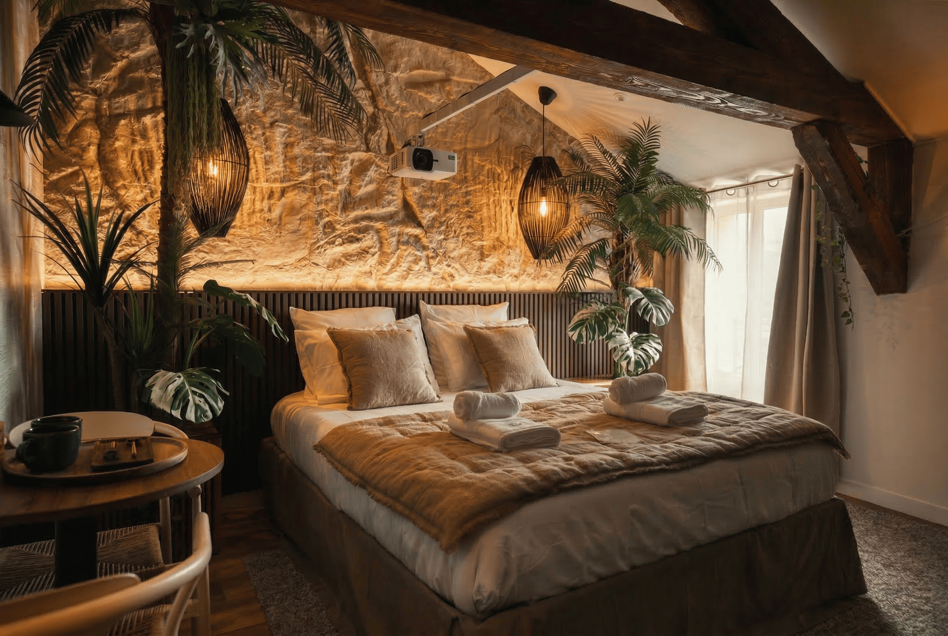 Suite Eden Jungle Room : lit sous un mur de pierre éclairé, palmiers et vidéoprojecteur